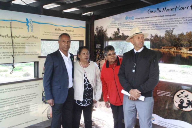 Representatives from the Noongar Kaartdijin Aboriginal Corporation and Rod Garlett standing in the John Masters Bird Hide in front of the display of Noongar artwork and history of Red Banks Pool before settlement.